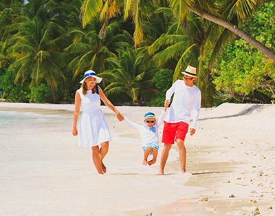 family with young child on tropical beach with palm trees